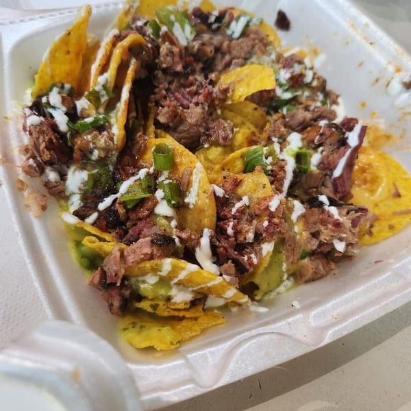 Smith Spot BBQ's pulled pork nachos, topped with white sauce, green onions, and guacamole.